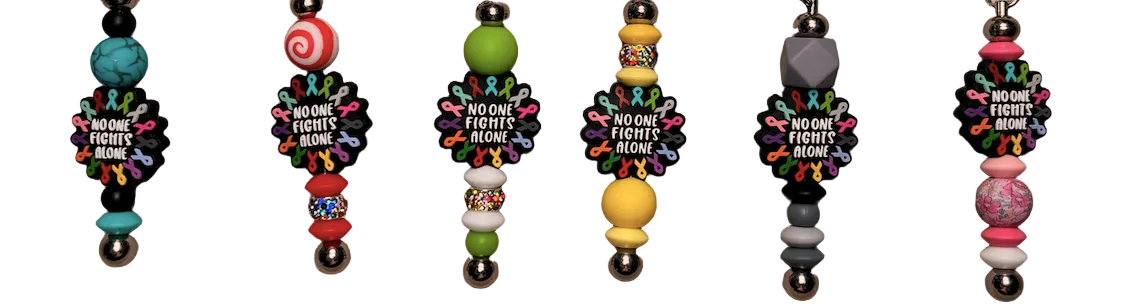 Row of colorful beaded keychains with motivational text on a textured surface